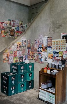 several boxes are stacked on top of each other in front of a wall covered with posters