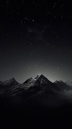 black and white photograph of the night sky with stars in the distance over snowy mountains