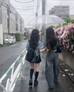 two girls walking down the street under an umbrella