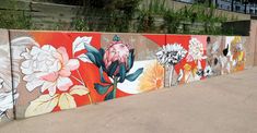 a wall painted with flowers and leaves on it's sides in front of a building