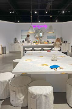 a white table with four stools and some pictures on the wall in the background