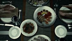 people sitting at a table with plates and silverware on it, including meats