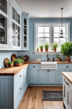 a kitchen with blue cabinets and wooden counter tops in front of a window filled with potted plants