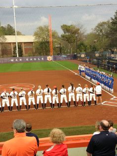 a group of people standing on top of a baseball field in front of a crowd