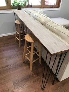 a counter with three stools next to it and a window in the back ground