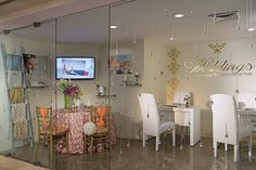 a glass walled dining room with white chairs and a television mounted on the wall in front of it