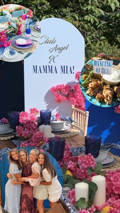 three women standing in front of a table with flowers and plates