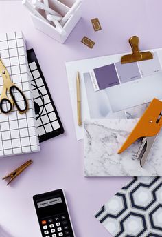 an assortment of office supplies on a purple surface with scissors, pens and paper clips