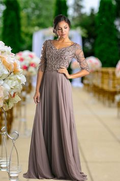 a woman in a long dress standing next to a flower filled aisle with chairs and flowers