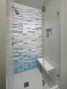 a walk in shower sitting next to a white sink and toilet under a window with blue tiles on the wall