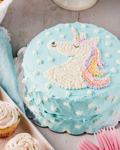 there is a blue cake with white frosting and a unicorn on it