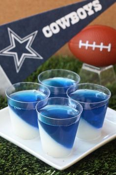 blue jello cups are sitting on a plate with a football in the background,