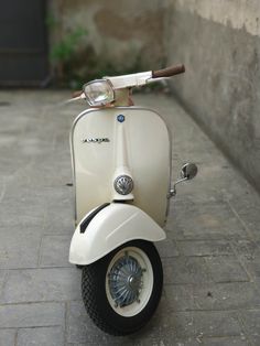 a white scooter is parked on the sidewalk