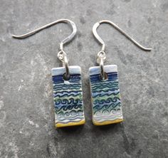 These dainty earrings have a design of waves pressed into the wet clay, which have been painted different shades of blue, green and turquoise, with a wash of soft blue across the sky, and bright yellow sand below.  As with all my jewellery they are made and decorated entirely by hand. After forming the drops from fine white clay, I imprint the designs. When dry, I sand the sides and back, round off the corners to ensure they are super smooth to the touch. They then have their first firing. Next Green And Turquoise, Beach Design, Bleu Turquoise, White Clay, Dainty Earrings, Blue Turquoise, Handmade Ceramic, Bright Yellow, Handmade Ceramics