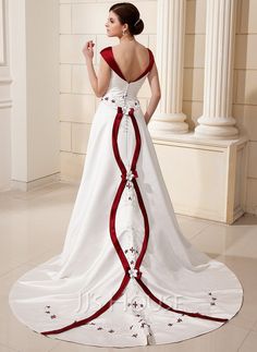 a woman in a white and red wedding dress standing on the floor with her back to the camera