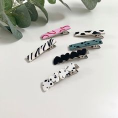 six different types of hair clips on a white table next to a potted plant