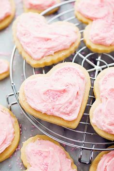 heart shaped cookies with pink frosting on a cooling rack