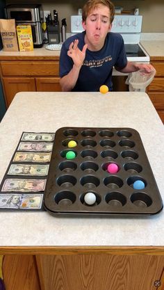 a young man sitting at a kitchen counter with an assortment of balls in front of him