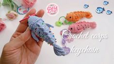 a hand holding a tiny crochet seahorse in front of small fish and flowers