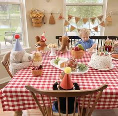 a little boy sitting at a table in front of a birthday cake with teddy bears on it