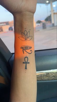 an egyptian symbol tattoo on the arm of a person in a car with a lotus