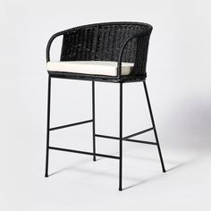 a black wicker bar stool with a white cushion on the seat and backrest