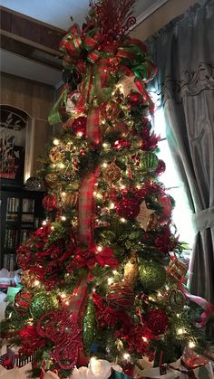 a christmas tree decorated with red, green and gold ribbons