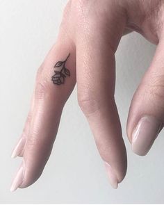 a woman's hand with a small black bird tattoo on her left thumb and finger