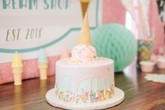 a birthday cake with sprinkles and ice cream on top sits on a table