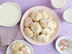 there are some cookies on the table with milk and sprinkles next to them