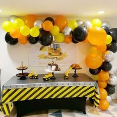 a table with black, white and yellow balloons on it