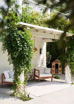 an outdoor living area with white furniture and greenery