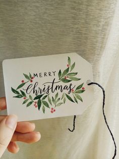 someone holding up a merry christmas card with holly leaves and berries on the front, which reads merry christmas