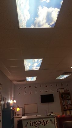 the ceiling in an office has been decorated with clouds and pictures on it, as well as a sign that says inspire