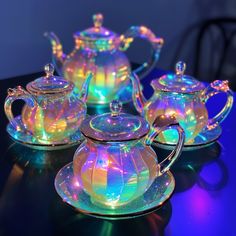 three glass teapots with lights on them are sitting on a table next to each other