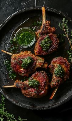 meat skewers with pesto sauce on a black plate next to some parsley