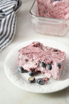 a piece of ice cream cake on a plate with blueberries and almonds around it