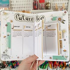 a person holding up a planner with the pages open to show their calendar and other things