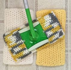 a green mop sitting on top of two yellow and white towels next to each other