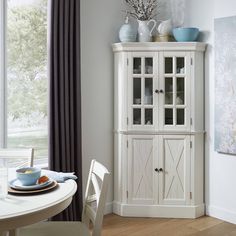 a white china cabinet sitting next to a window