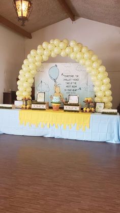 a winnie the pooh birthday party with balloons and desserts on a long table