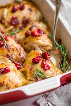 a casserole dish with chicken and cranberries in it, garnished with rosemary