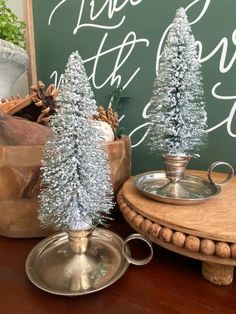 silver tinsel christmas trees sitting on top of a wooden table