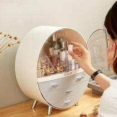 a woman is looking at the inside of a white cabinet