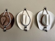 Elevate your space with these beautifully handcrafted cowboy hat hangers, designed for both functionality and style. Made from durable, thick rope with sturdy leather accents, these hangers feature sleek metallic rivets and finely crafted leather beads at the ends, offering a rustic yet elegant way to display your favorite hats. The minimalist design ensures that your hats are the true stars of the show, while the textured rope and leather give a nod to the rugged charm of Western living. Perfect for any cowboy or cowgirl looking to add a touch of rustic flair to their home decor, these hangers not only provide a secure hold for your hats but also act as an eye-catching decorative piece on your wall. Whether you hang one or several together, these hangers make a great gift or a stylish upg Cowboy Hat Hanger, Hat Hangers, Cowboy Hut, Leather Beads, Texas Wall Art, Hallway Art, Cowgirl Look, Boy Wall Art, Hat Hanger