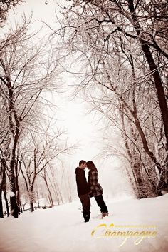 two people standing in the snow near trees