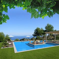 an outdoor swimming pool with lounge chairs and umbrellas on the lawn next to it