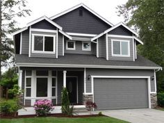 a gray house with white trim and two car garages on the front door is shown