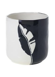 a black and white cup with a leaf on it