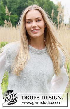 a woman with long blonde hair standing in front of tall grass and looking at the camera